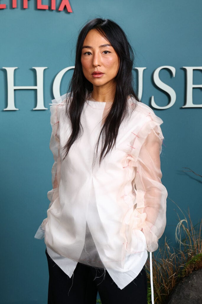 Close-up of Greta Lee's The Row shirt featuring sheer tulle sleeves with exposed red basting stitches at 'The Last House' photocall.