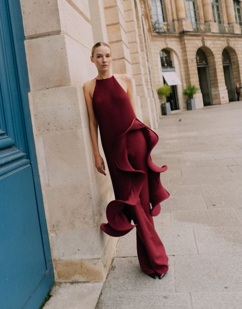 J’amemme Loulou red plissé maxi dress styled with matching red trousers from the designer’s lookbook.