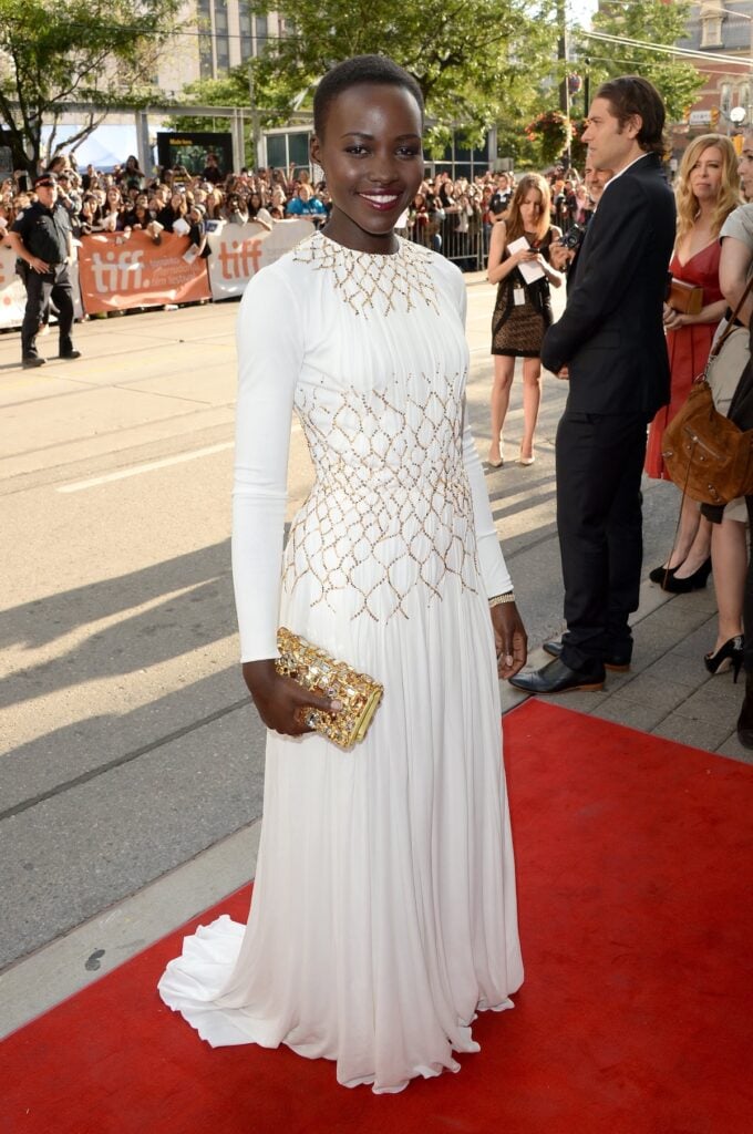 Lupita Nyong'o arrives at the "12 Years A Slave" Premiere during the 2013 Toronto International Film Festival in white Prada dress