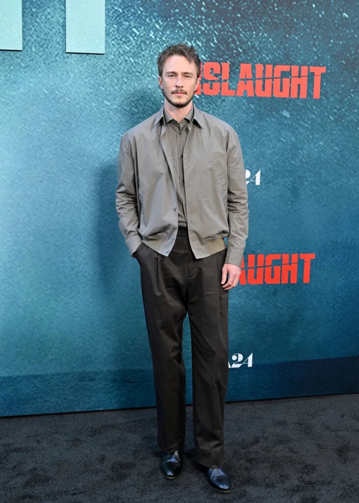 Drew Starkey wears a taupe Hermès jacket with brown trousers to the Onslaught LA premiere.