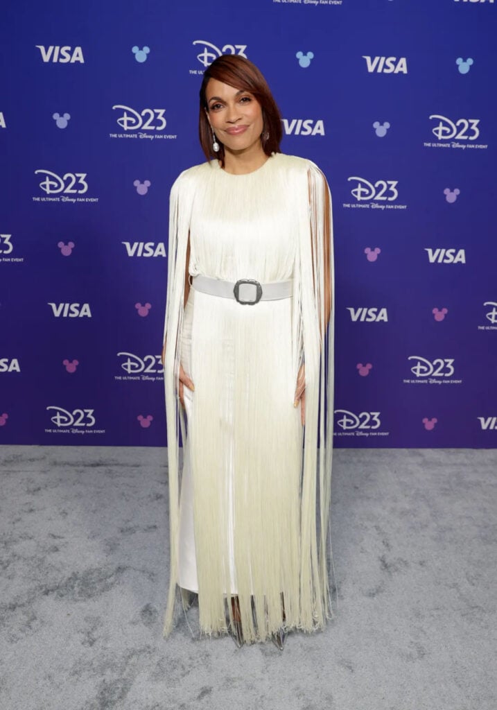 Rosario Dawson wears a white fringed Lein Studio dress at the D23 Expo 2026 in Anaheim for 'Ahsoka' Season 2.