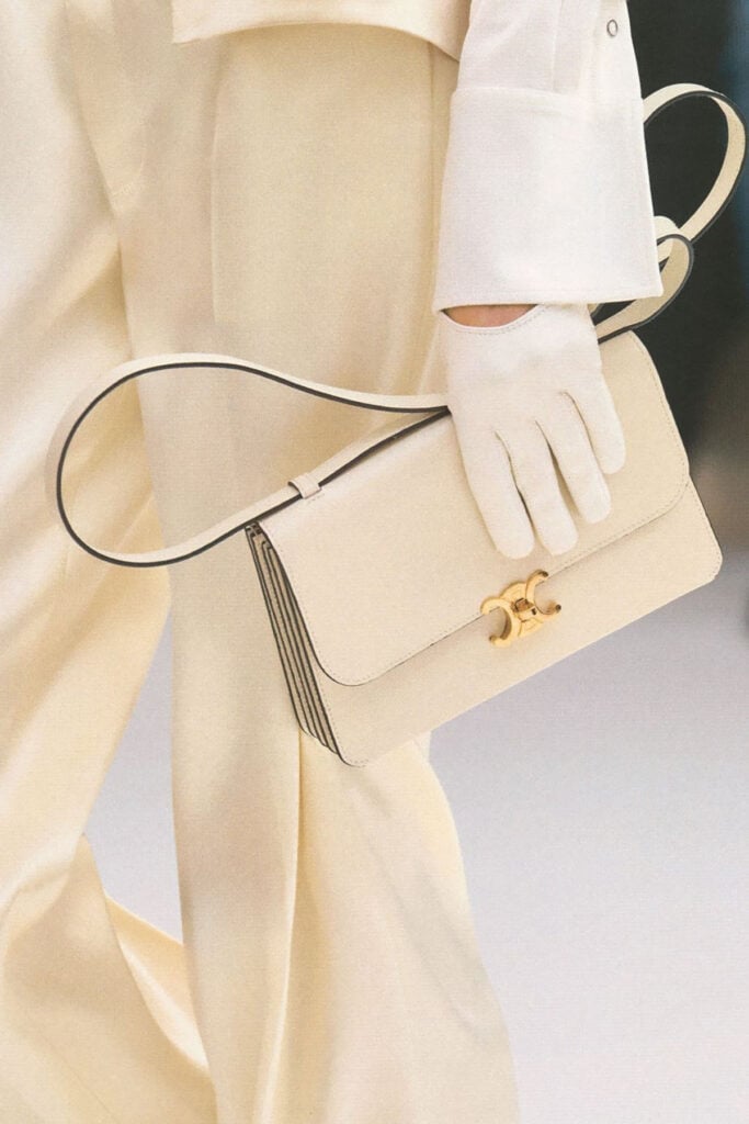 Celine 17 bag in cream leather featuring accordion sides, a top handle and distinctive gold Triomphe hardware.