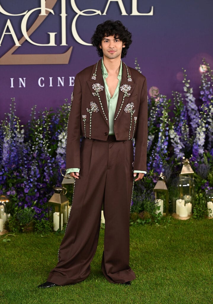 Xolo Maridueña wears brown tailoring with crystal floral embellishments and a mint-green shirt at the Practical Magic 2 London photocall.