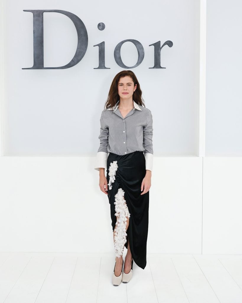 Alison Oliver wearing a black Dior dress with floral detail at the Dior Spring 2027 show in Paris.