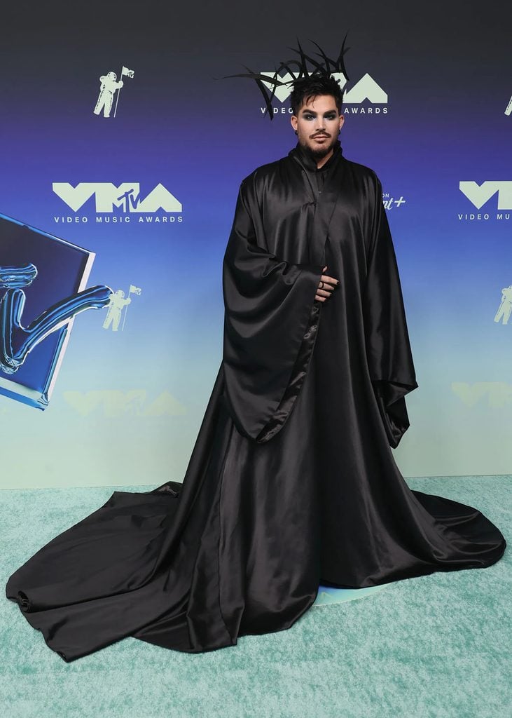 Adam Lambert wearing a custom Charles de Vilmorin Couture black silk taffeta cape with a black-tinted rooster-feather headpiece at the 2026 MTV VMAs.