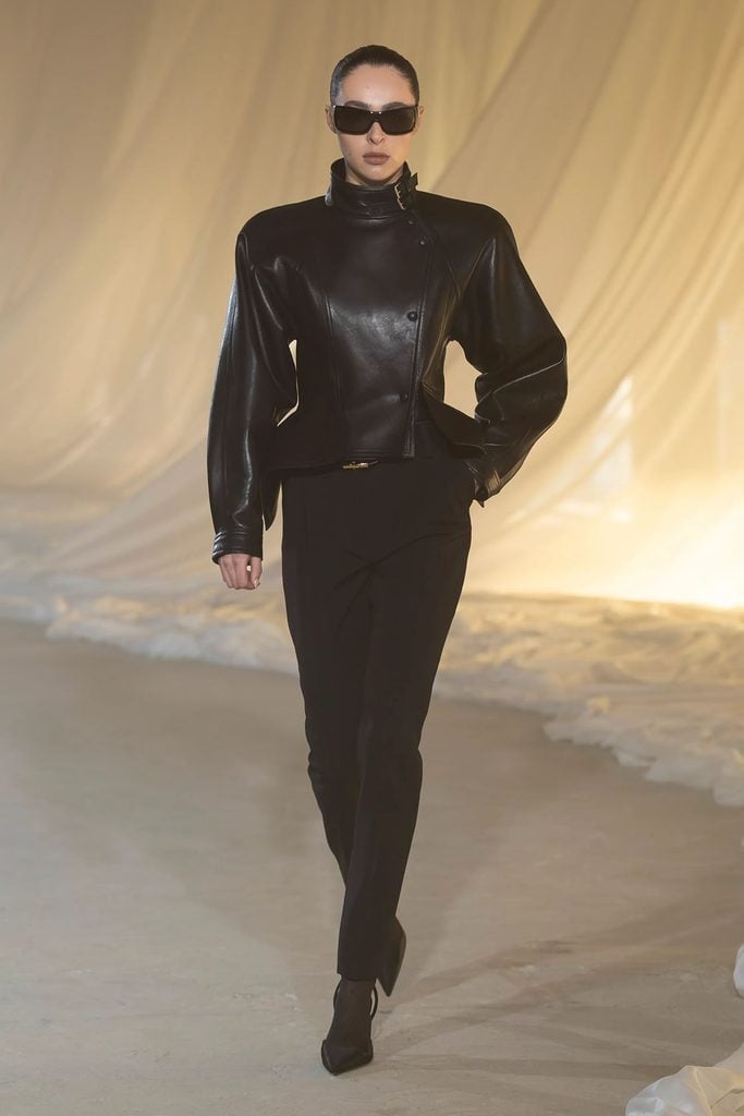Balmain Fall 2026 black leather jacket with structured shoulders and asymmetrical fastening shown on the runway.