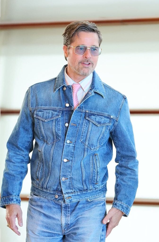 Brad Pitt in double denim with a pink-and-white striped shirt, pink tie and Jacques Marie Mage Jagger aviator sunglasses at The Heart of the Beast photocall in San Sebastián