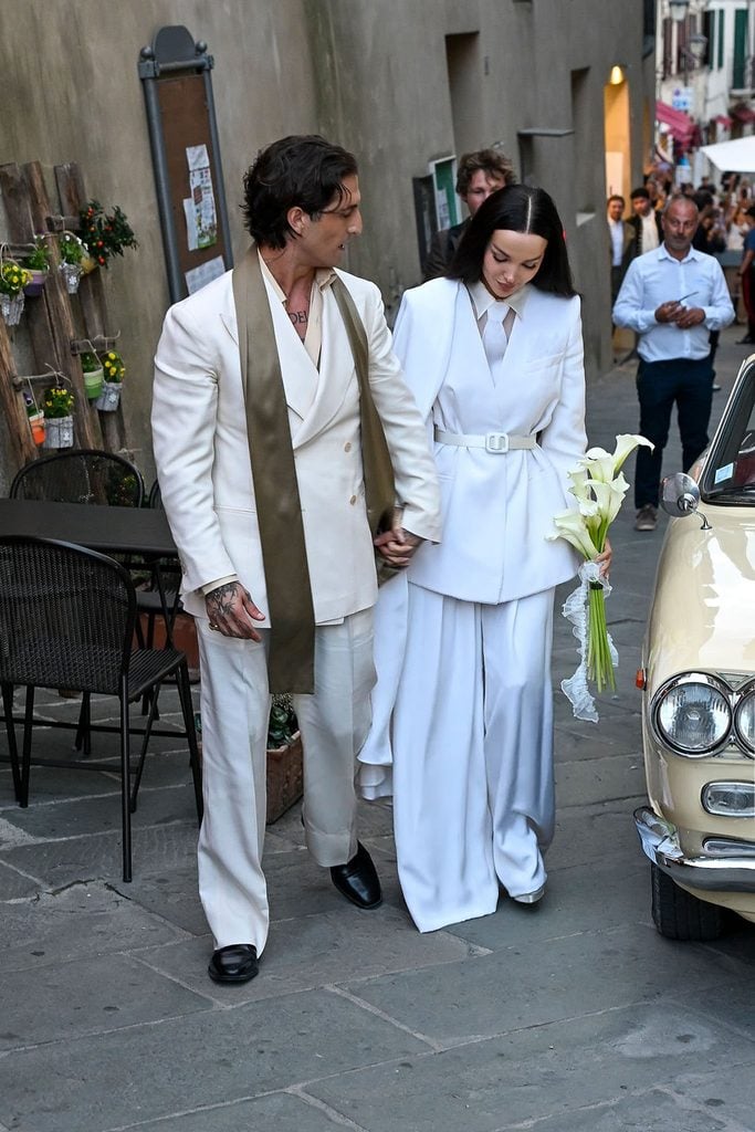 Newlyweds Dove Cameron and Damiano David beside a vintage car following their wedding in Montalcino, Italy.
