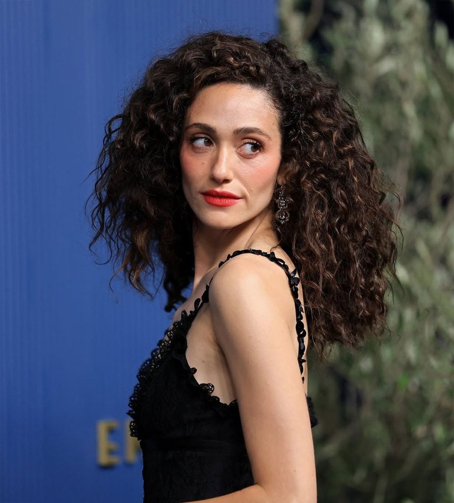 Emmy Rossum’s curly hairstyle and red lip complement her black Julie de Libran look at the 2026 Emmy Awards.