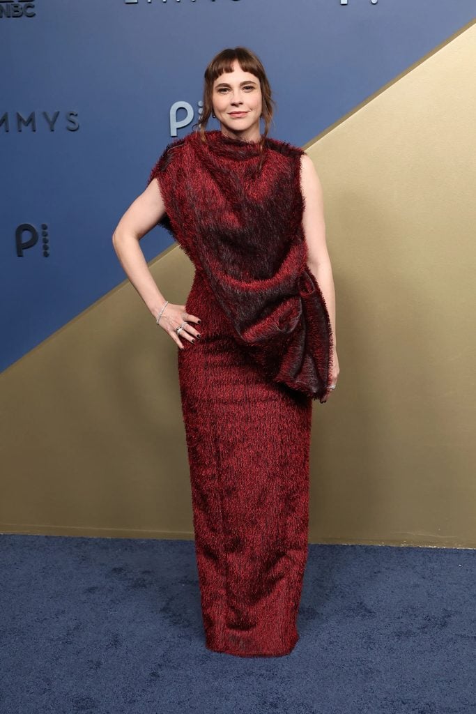 Fiona Dourif wearing a textured deep-red Thomas Hanisch gown with a sculptural silhouette at the 2026 Emmy Awards.
