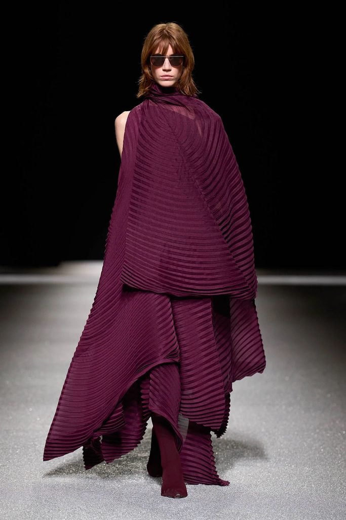 Issey Miyake Fall 2026 runway look featuring the burgundy pleated dress later worn by Cynthia Nixon.
