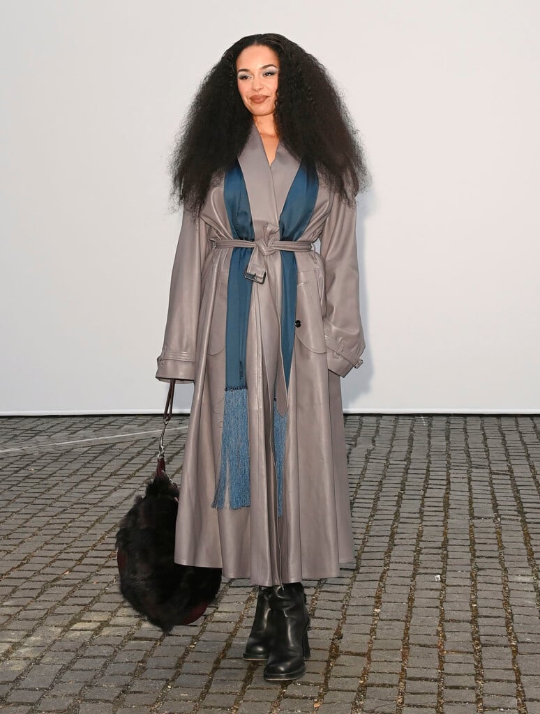 Jorja Smith wearing a grey leather Burberry trench coat with a fringed scarf at the Burberry Summer 2027 show in London