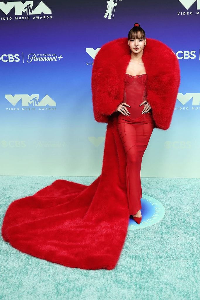 Lisa wearing a red Quine Li faux-fur coat over a corseted The Attico dress at the 2026 MTV VMAs.