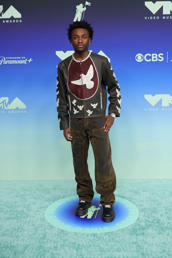 Miles Caton wearing a KidSuper Fall 2026 graphic leather jacket with distressed brown trousers at the 2026 MTV VMAs.