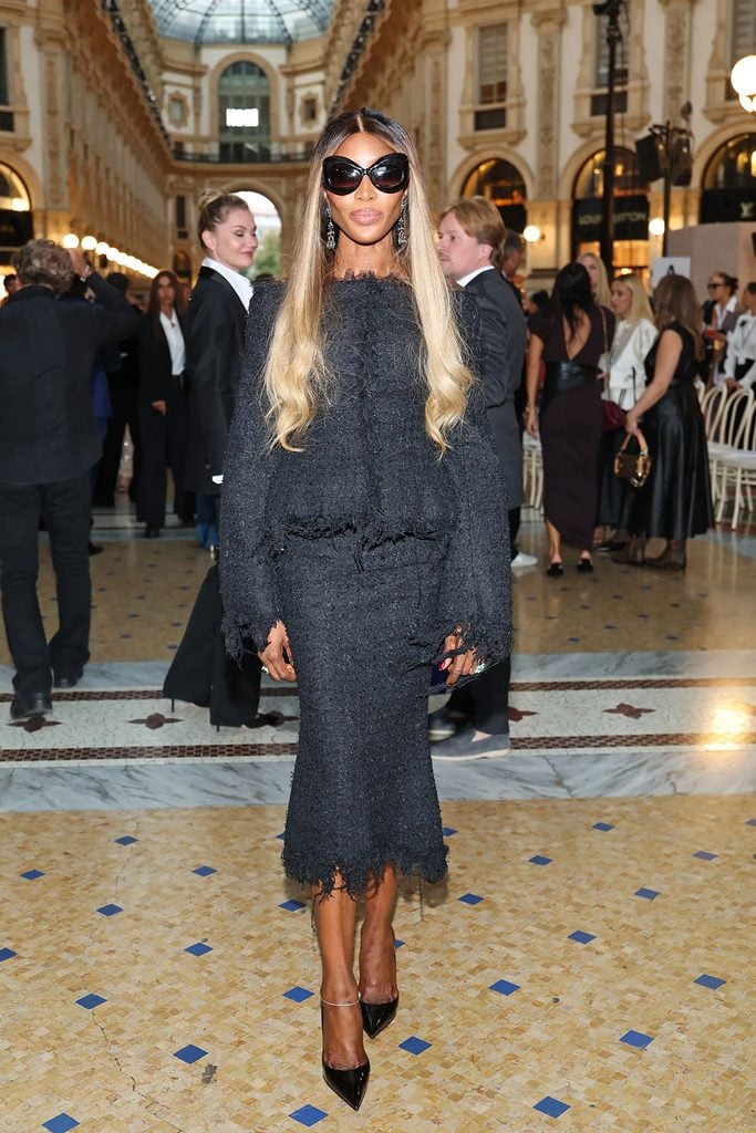 Naomi Campbell wearing a black Matières Fécales tweed jacket and midi skirt with oversized sunglasses at Vogue World Milano.