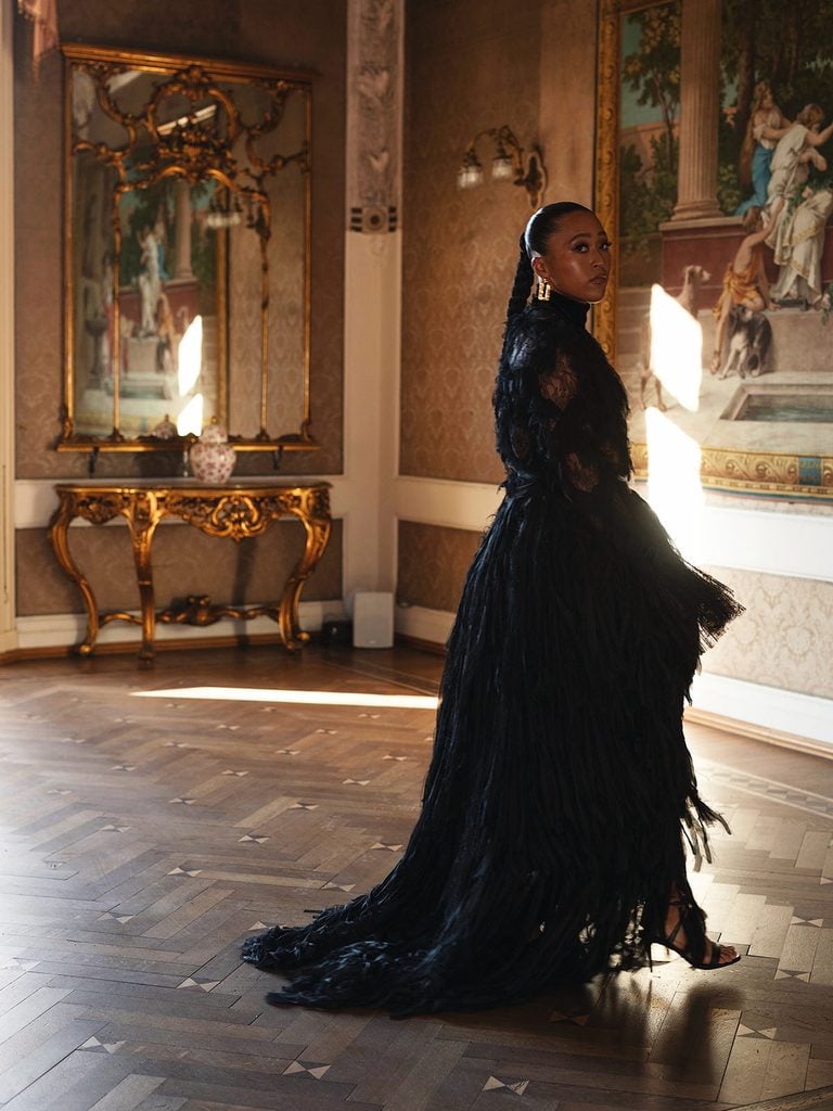 Naomi Osaka in a sheer black Roberto Cavalli blouse and full crinoline skirt with gold earrings at Vogue World Milano side view