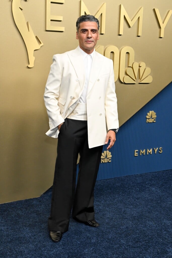 Oscar Isaac in a white Celine tuxedo jacket, matching cummerbund and black trousers on the Emmys red carpet.