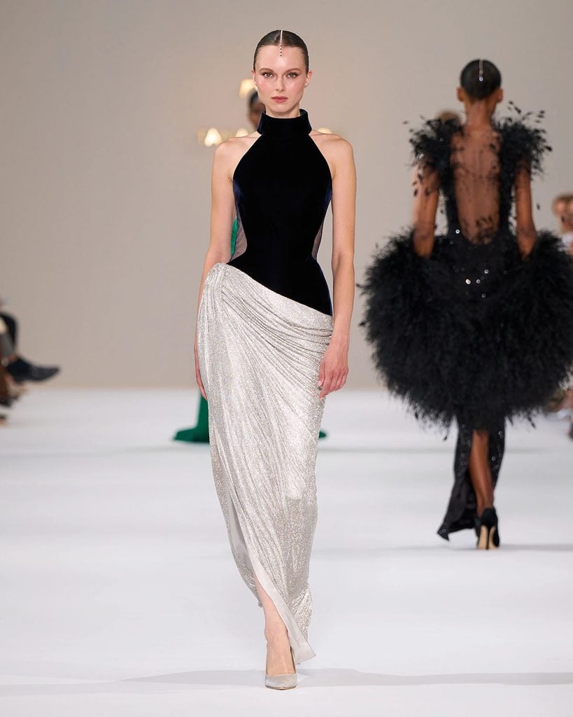 Tamara Ralph Fall 2026 Couture navy velvet halterneck gown with an asymmetric silver crystal-mesh skirt on the runway.