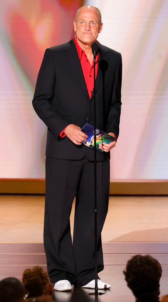 Woody Harrelson wearing a black Celine suit with a red shirt while presenting at the 2026 Emmy Awards.