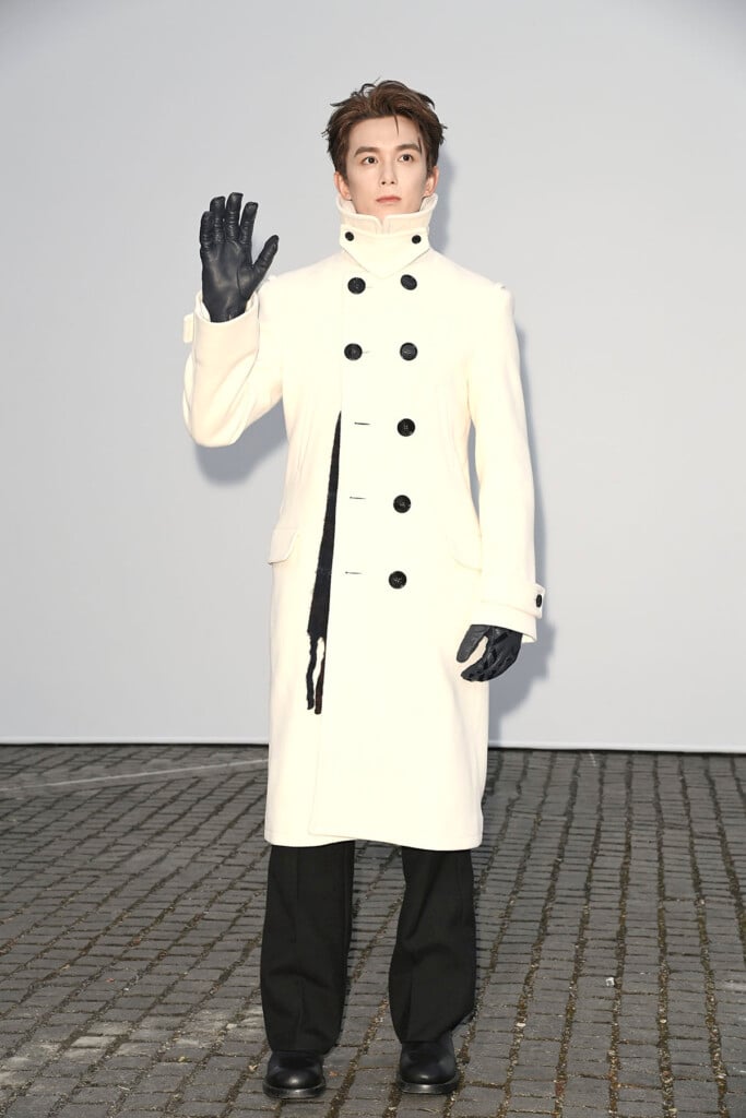 Wu Lei wearing a cream Burberry coat with black leather gloves at the Burberry Summer 2027 show in London