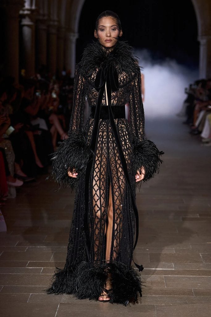 Zuhair Murad Fall 2026 Couture sheer black embroidered coat-gown with feathered collar, cuffs and hem on the runway.
