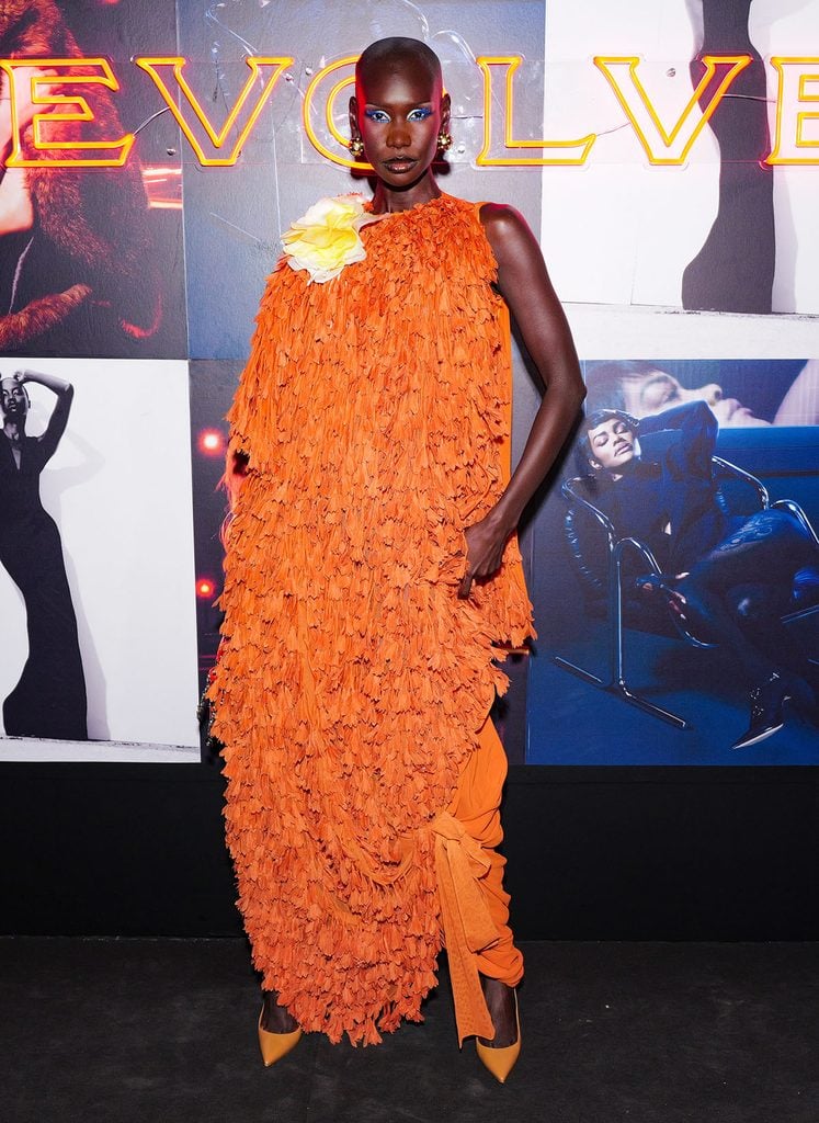 Adot Gak wearing an orange Dior Resort 2027 dress at the REVOLVE Magazine launch during Paris Fashion Week.
