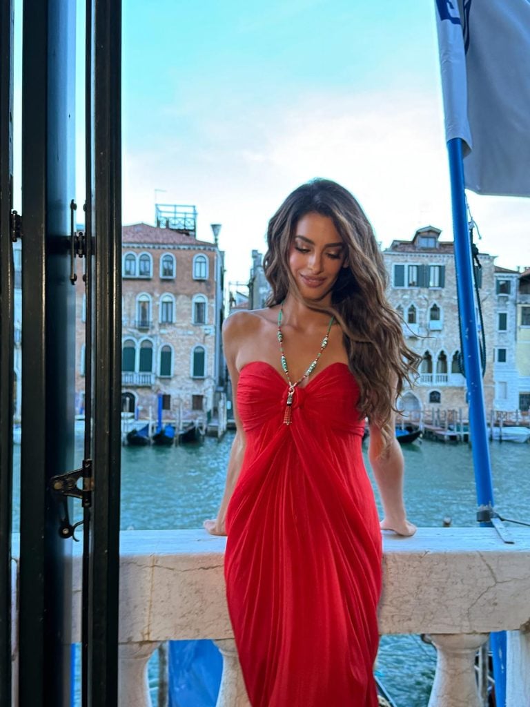 Amal Clooney wearing a vintage red chiffon gown with Cartier jewellery at the Cartier Cinema Club during the 2026 Venice Film Festival.