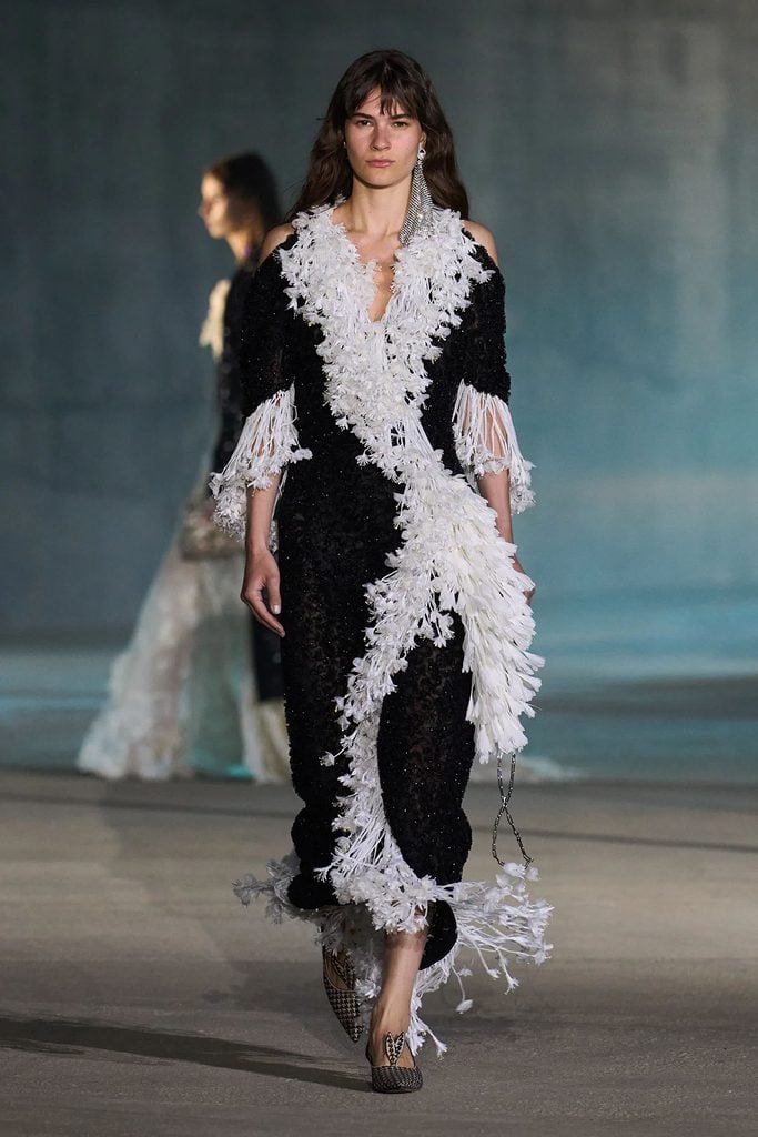 Dior Resort 2027 black embroidered dress with asymmetric white fringe detailing on the runway.