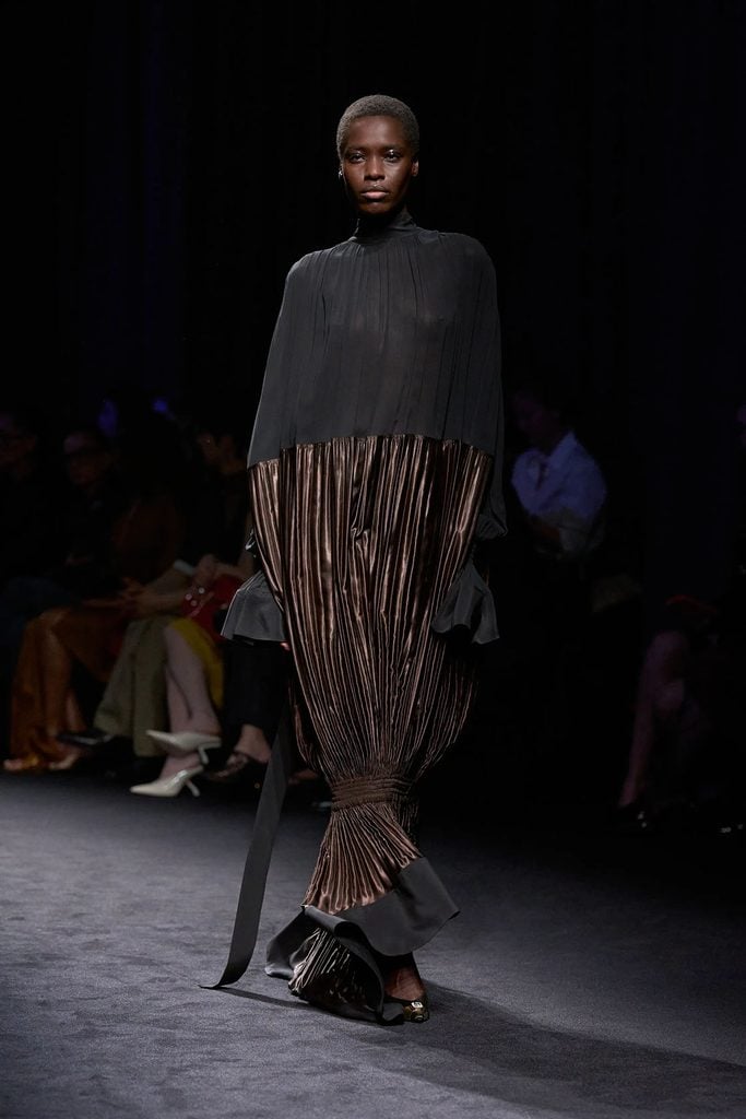 Ferragamo Fall 2026 black chiffon and metallic brown pleated dress with a dramatically tapered skirt on the runway.
