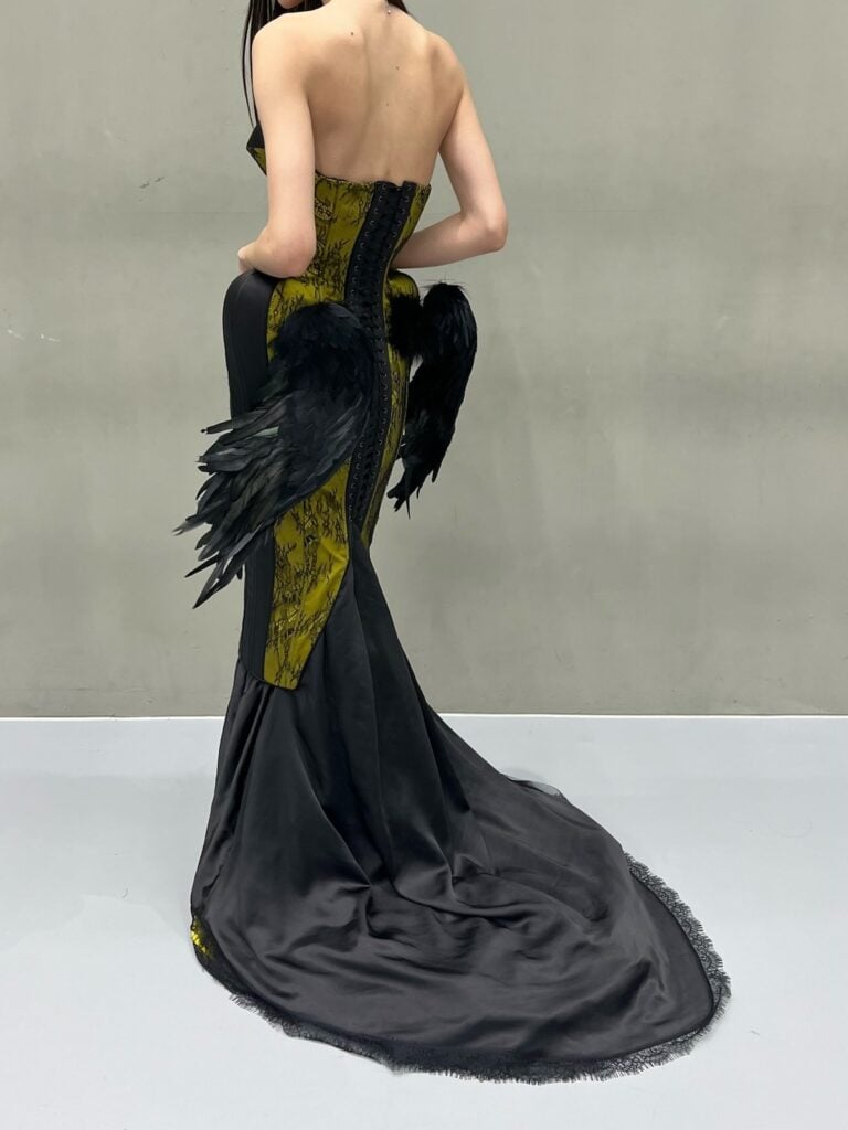 Back view of Joey King’s Ilya Mingmoon dress showing the lace-up corset, feathered wings and black satin train.