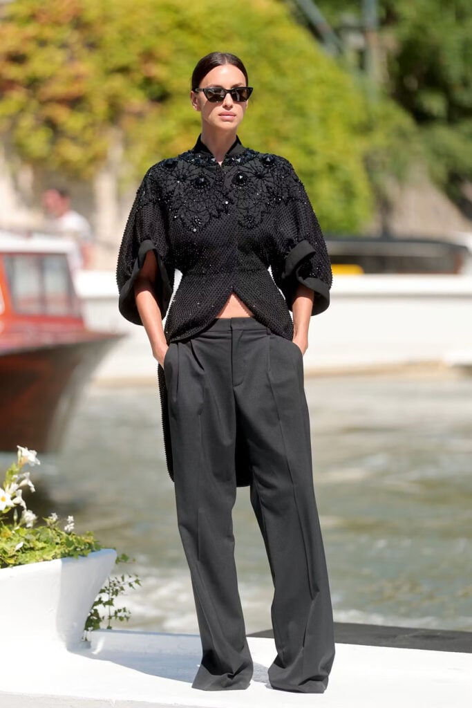 Irina Shayk wearing an archival Givenchy Fall 2015 embroidered jacket and black trousers arriving at Hotel Excelsior in Venice.