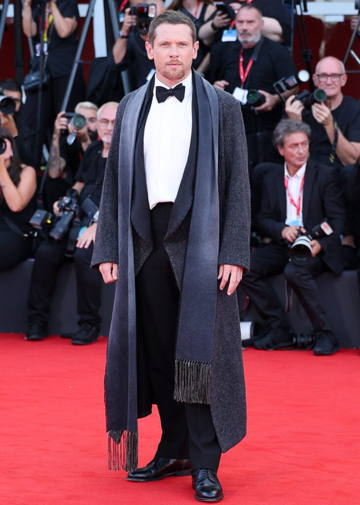 Jack O’Connell wearing a layered grey Dior look with a tuxedo jacket, wool coat and scarf at the Ink premiere in Venice.