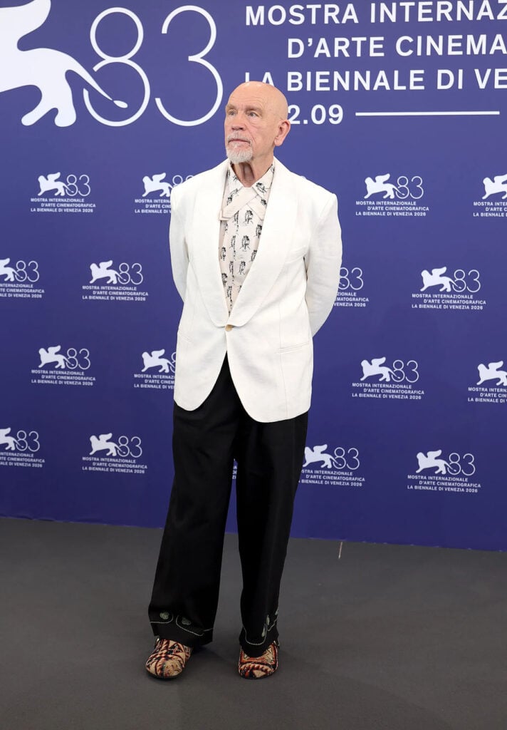John Malkovich wearing a Giuliva Heritage blazer with Bode trousers and King Kennedy mules at the Wild Horse Nine Venice Film Festival photocall.