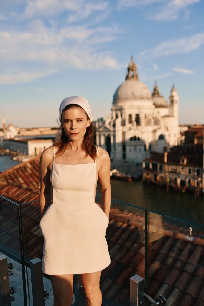 Kate Mara wearing a white Calvin Klein Collection mini dress and satin headscarf at the Cartier Cinema Club in Venice.