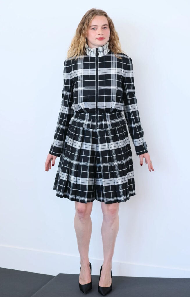 Luna Wedler wearing a black-and-white checked Louis Vuitton peplum jacket and pleated shorts at the La Ragazza Con La Leica Venice Film Festival photocall.