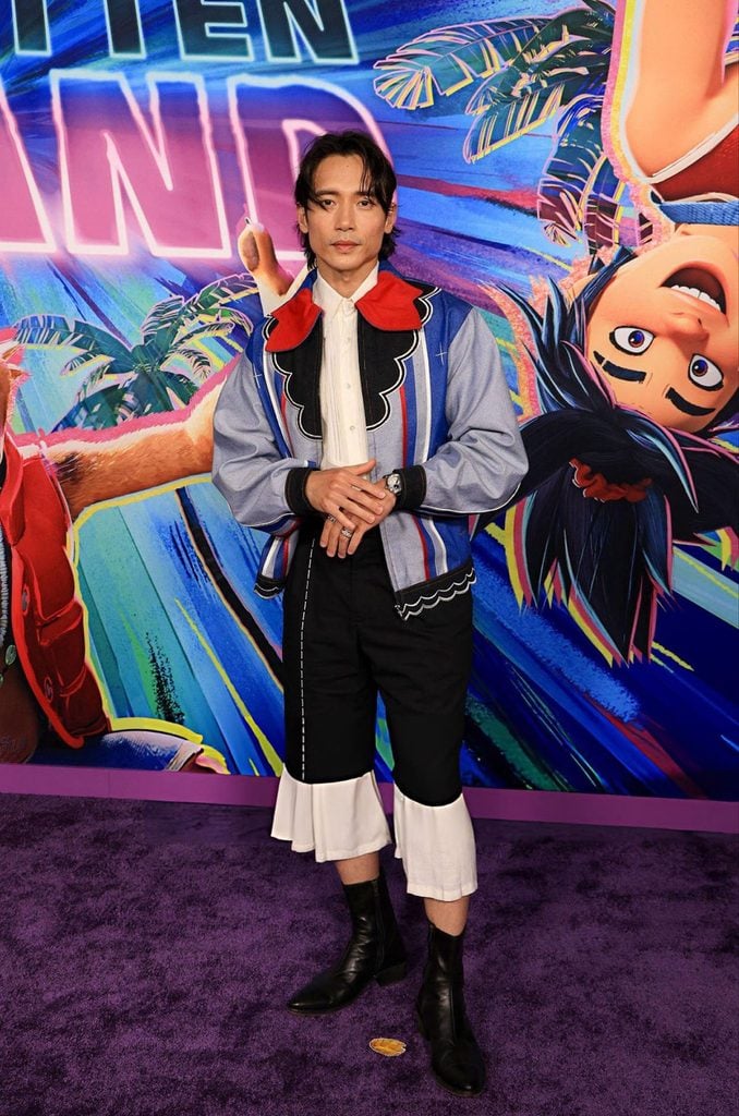 Manny Jacinto wearing a Randolf jacket with striped panels and a red collar with cropped black-and-white trousers at the Forgotten Island premiere in Los Angeles.