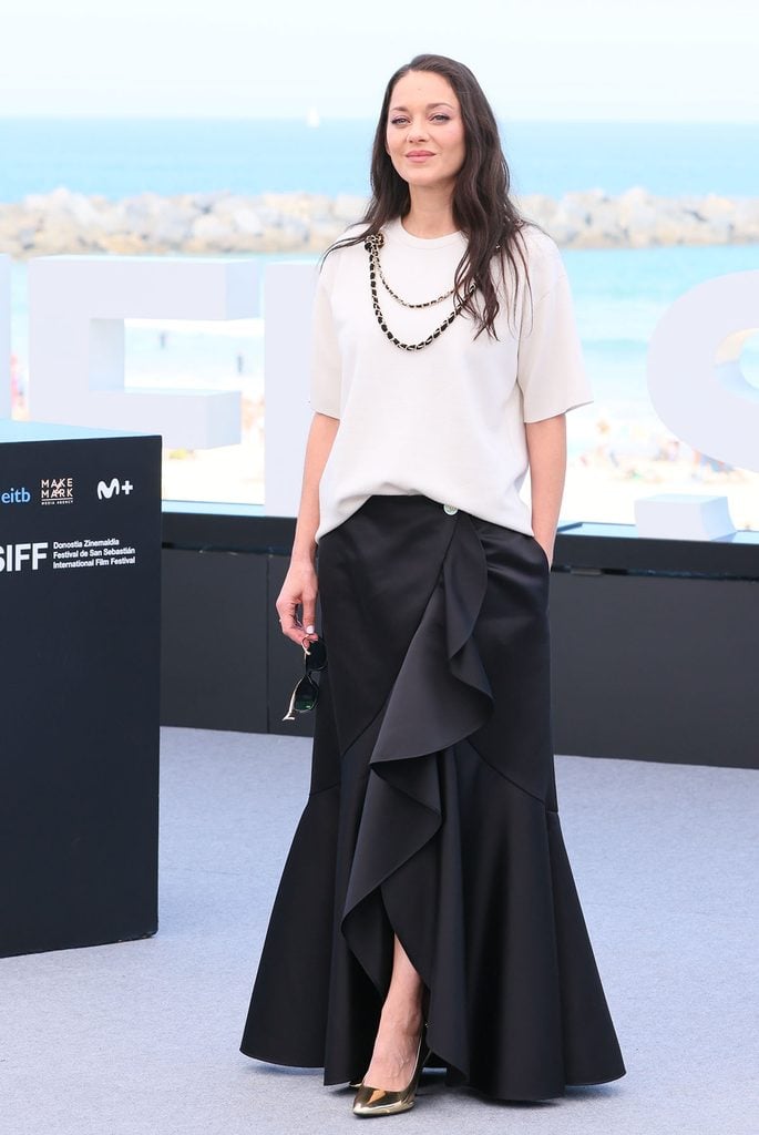 Marion Cotillard wearing an ecru Chanel top with a cascading black satin skirt and metallic pumps at the San Sebastián International Film Festival.