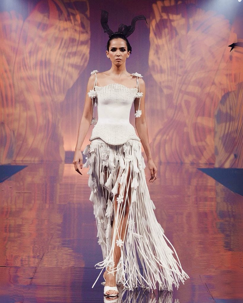 Mark Bumgarner runway look featuring a white corseted bodice with floral appliqués and a dramatic fringed skirt.