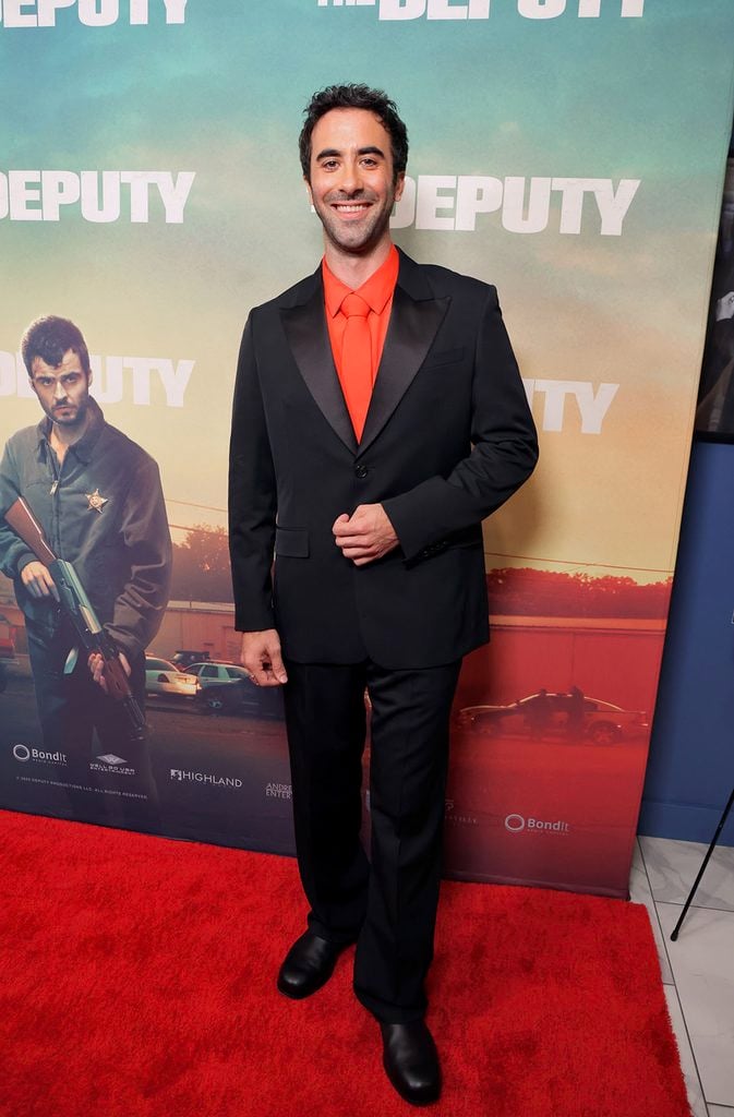 Matt Sukkar wearing a black Loewe suit with a tonal red shirt and tie at The Deputy screening in Los Angeles