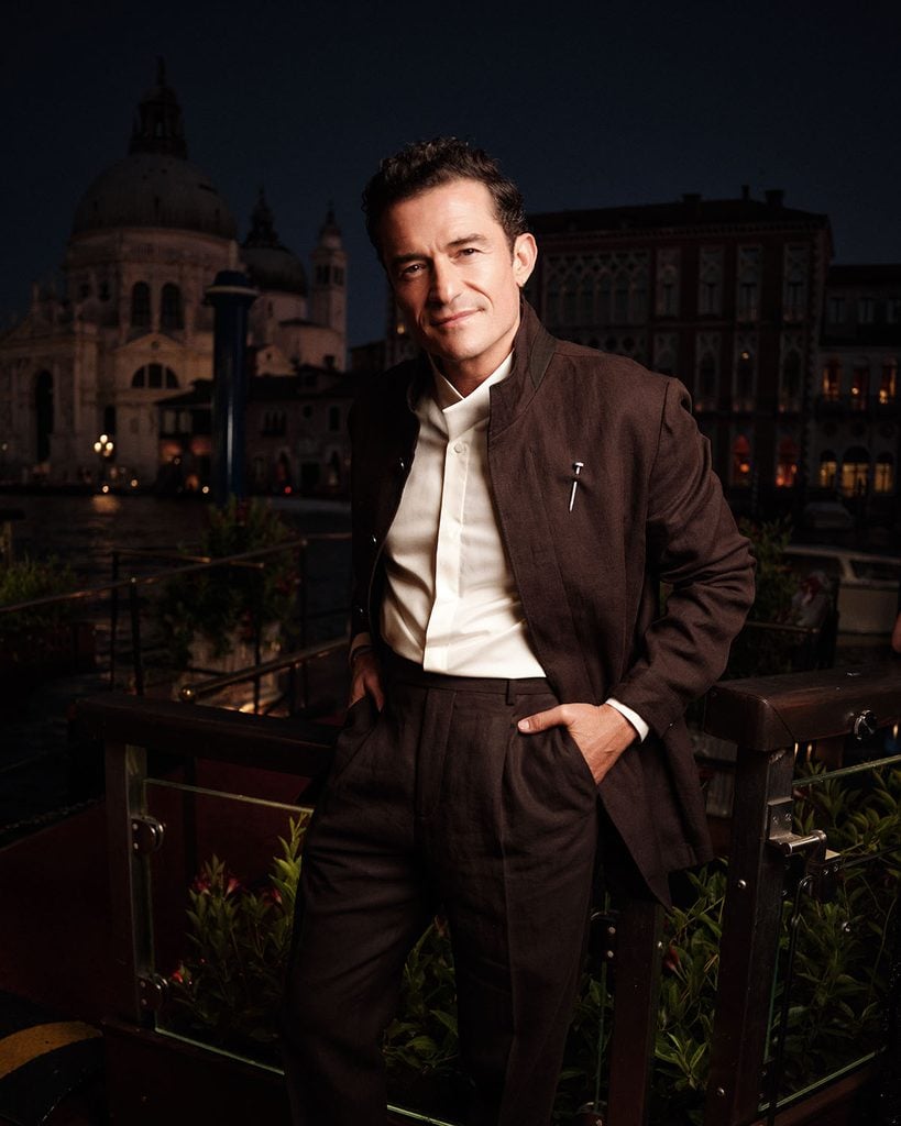 Orlando Bloom wearing brown tailoring with a Cartier pin at the Cartier Cinema Club during the Venice Film Festival.