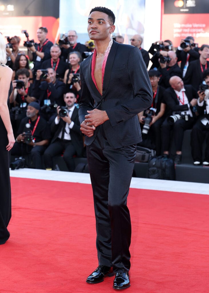 Owen Thiele wearing black tailoring with a red-and-white printed scarf and Pandora jewellery at the Ink premiere in Venice.