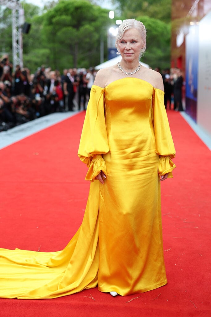 Pamela Anderson in a yellow Carolina Herrera gown at the Place to Be premiere.