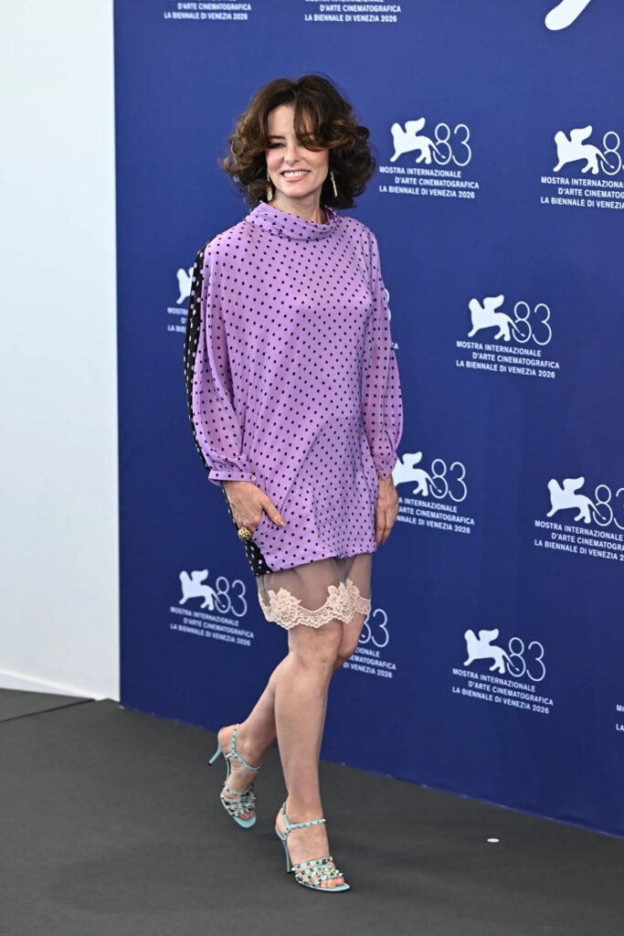 Parker Posey wearing a lilac polka-dot Valentino Pre-Fall 2026 dress at the Wild Horse Nine photocall during the Venice Film Festival.