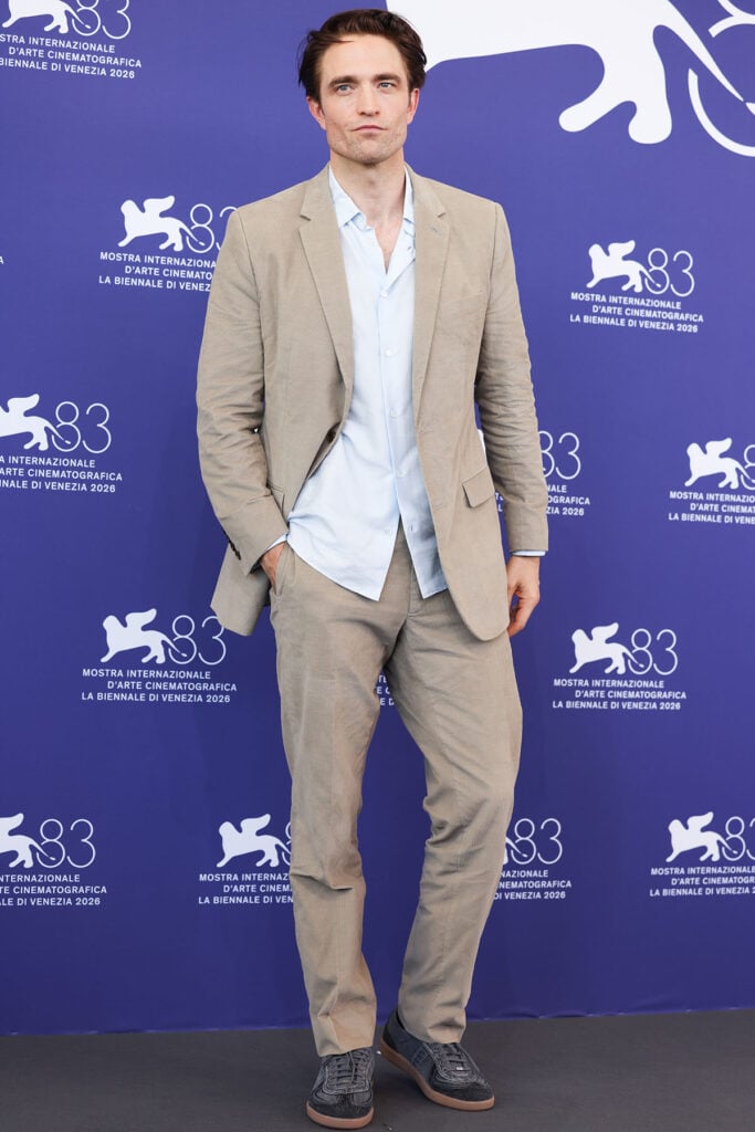 Robert Pattinson wears a beige Dior suit with a pale blue shirt and black denim sneakers at the Primetime photocall during the Venice Film Festival.