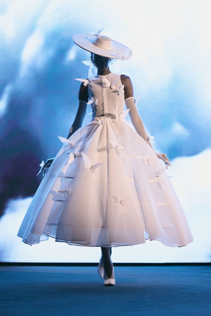 A model wears Robert Wun’s white butterfly gown with sheer gloves from the Spring 2026 Couture collection.