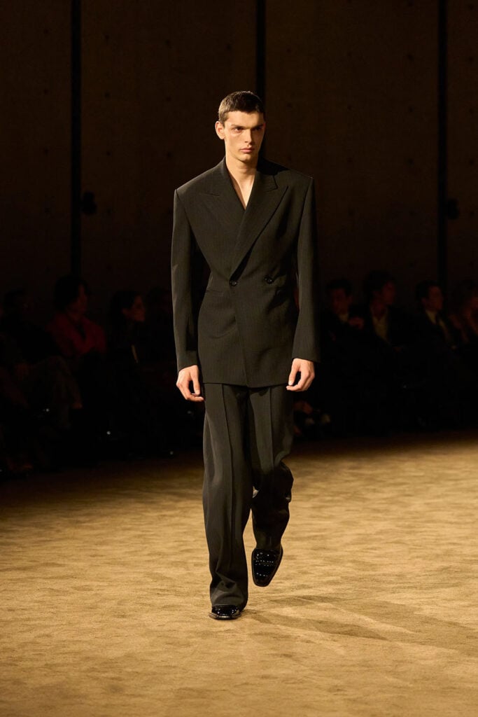 Saint Laurent Fall 2026 black pinstripe suit with strong shoulders and wide-leg trousers on the runway.