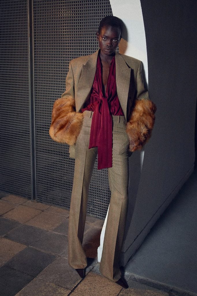 Saint Laurent Pre-Fall 2026 Prince of Wales check suit styled with a burgundy blouse and faux-fur cuffs in the lookbook