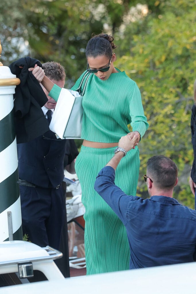 Taylor Russell wearing a green Pleats Please Issey Miyake two-piece on arrival at the 2026 Venice Film Festival.