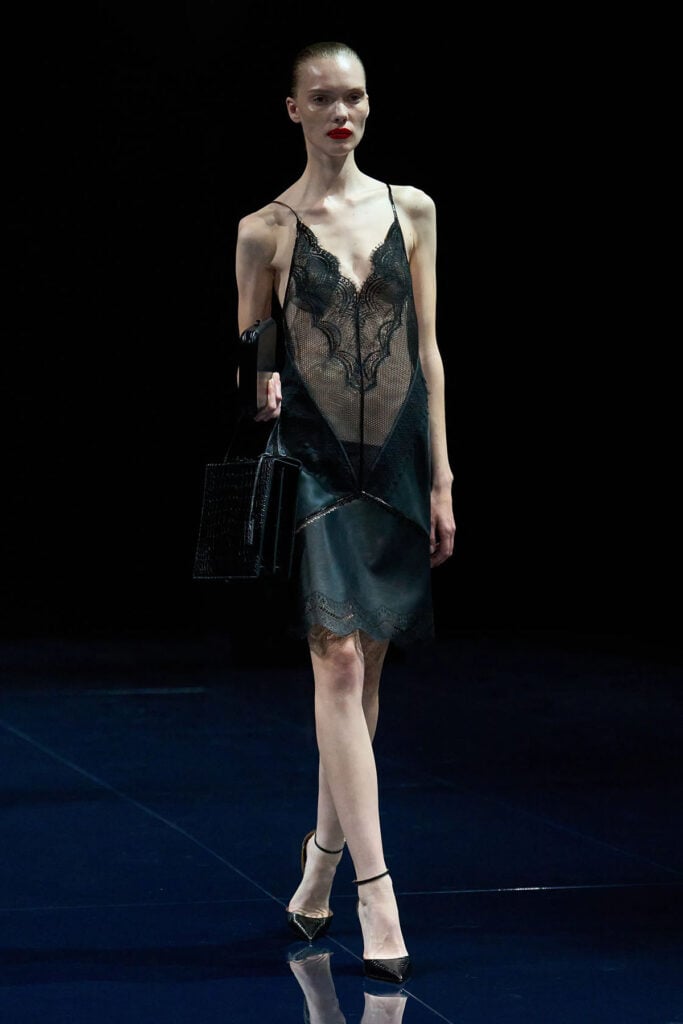 A model wears the black lace and leather Tom Ford by Haider Ackermann Spring 2026 look on the runway.