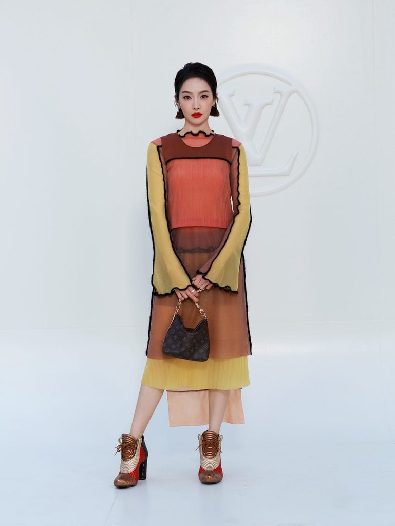 Victoria Song wearing layered orange and yellow Louis Vuitton separates at the Spring-Summer 2027 show in Paris.